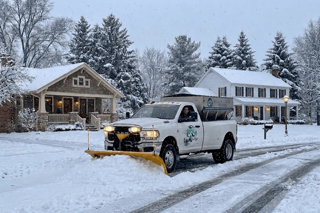 Snow plow truck clearing a snow-covered residential street during winter storm — commercial snow removal service