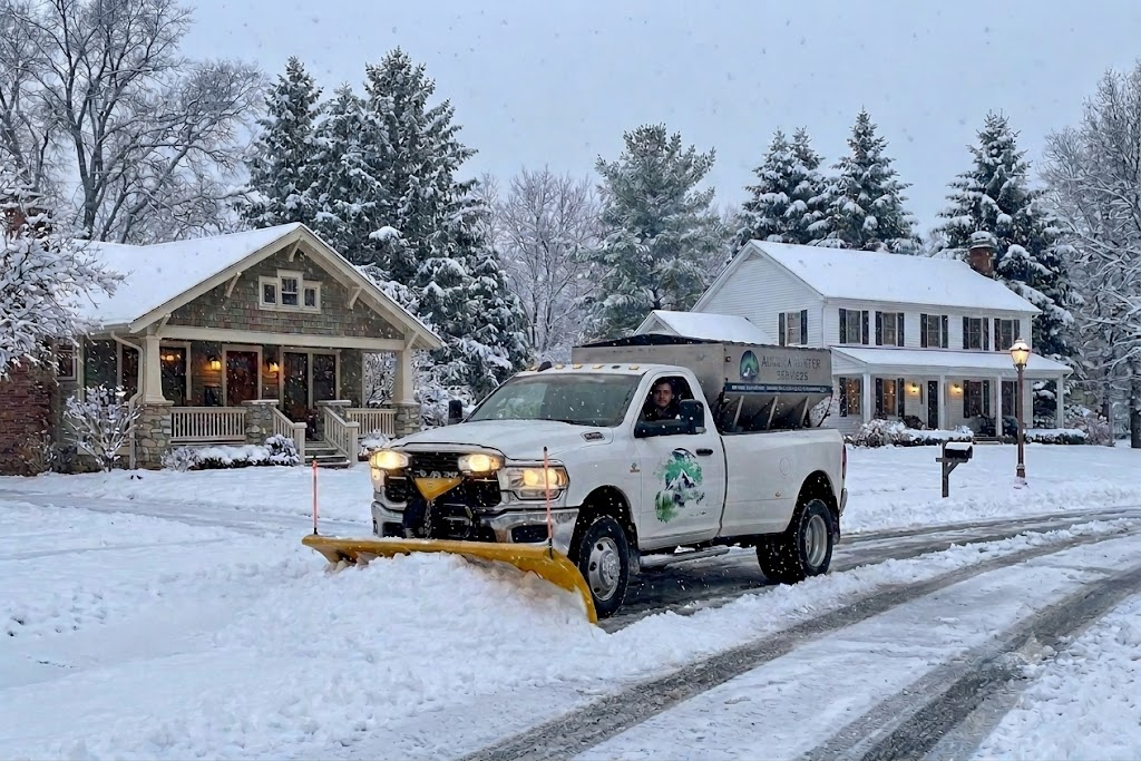 Snow plow truck clearing a snow-covered residential street during winter storm — commercial snow removal service